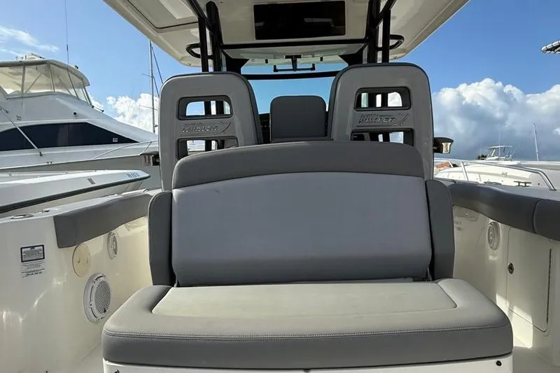 Slide: The Image of 2023 Boston Whaler 330 Outrage boat interior with cushioned seating and clear sky background. - 6
