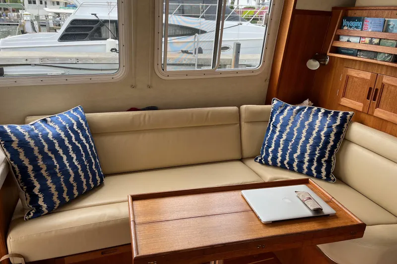 Slide: The Image of Cozy interior of 2005 Nordic Tug 37 Flybridge featuring an L-shaped Ultraleather sofa with blue cushions and Teak table. - 28