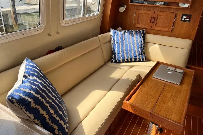 Slide: The Image of 2005 Nordic Tug 37 Flybridge interior with beige Ultraleather sofa, blue cushions, and wooden table. - 29