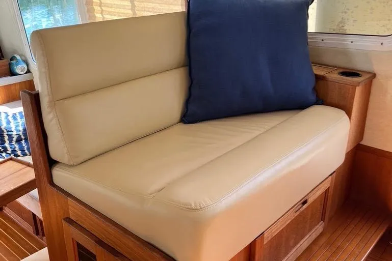 Slide: The Image of Companion Seating in Pilothouse to port side featuring Beige Ultraleather seating with blue cushion on 2005 Nordic Tug 37 Flybridge yacht interior. - 35