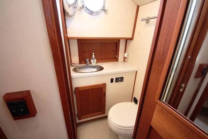Slide: The Image of 2005 Nordic Tug 37 Flybridge bathroom with sink, toilet, and wooden cabinetry. - 56