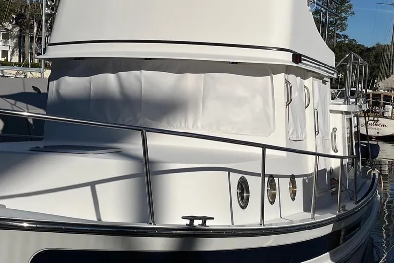 Slide: The Image of 2005 Nordic Tug 37 Flybridge boat with white exterior and railings in a marina. - 6