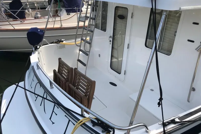 Slide: The Image of 2005 Nordic Tug 37 Flybridge Cockpit featuring Swim platform, Stainless Steel Hand railing, teak folding chairs, built-in dunnage storage box and overheard hardtop - 8