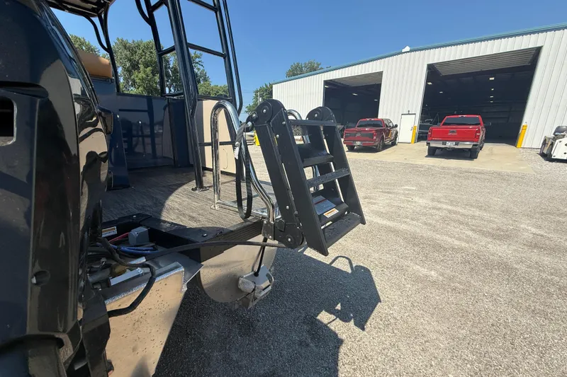 Slide: The Image of 2025 Tahoe Pontoon Cascade Cruise Funship ladder near a garage with trucks. - 3