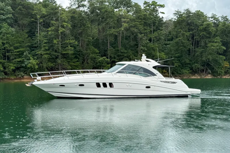 Slide: The Image of 2007 Sea Ray 48 Sundancer yacht cruising on a serene lake with lush forest backdrop. - 1