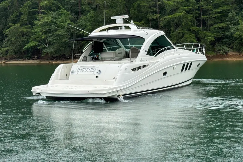 Slide: The Image of 2007 Sea Ray 48 Sundancer yacht cruising on a serene lake with lush green trees. - 10