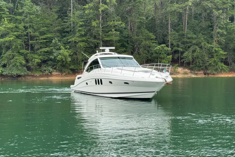 Slide: The Image of 2007 Sea Ray 48 Sundancer yacht cruising on a serene lake with lush forest backdrop. - 19