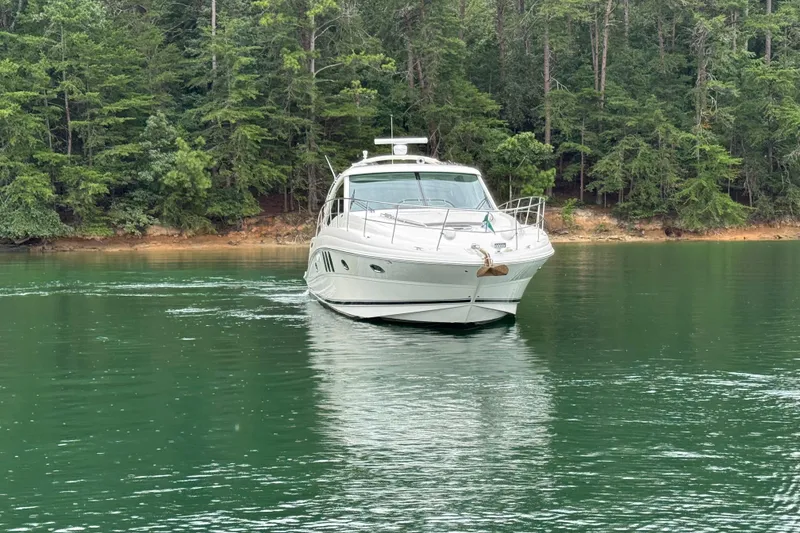 Slide: The Image of 2007 Sea Ray 48 Sundancer yacht cruising on a serene lake with forested shoreline. - 21