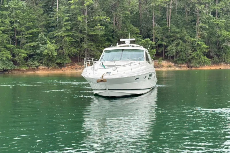 Slide: The Image of 2007 Sea Ray 48 Sundancer yacht cruising on a serene lake with forested shoreline. - 23