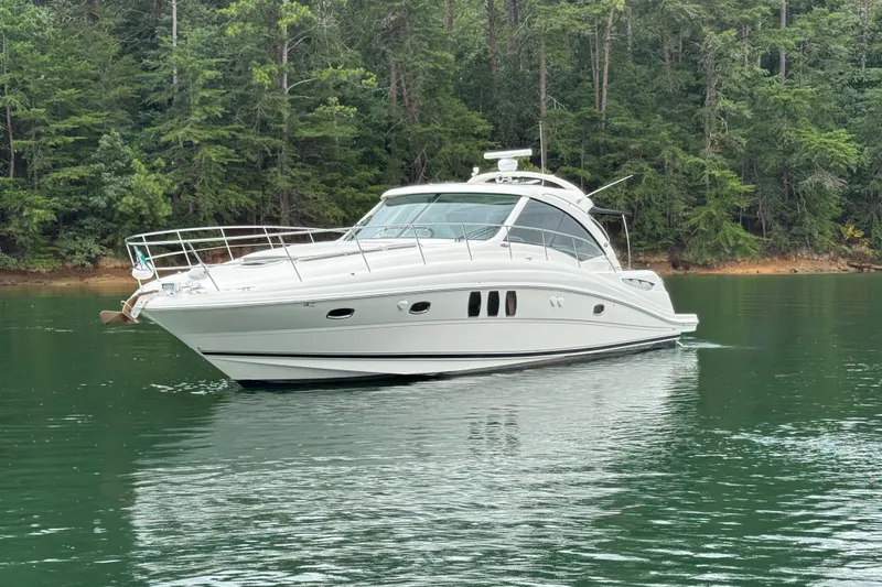 Slide: The Image of 2007 Sea Ray 48 Sundancer yacht cruising on a serene lake with lush forest backdrop. - 26