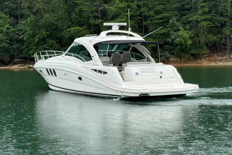 Slide: The Image of 2007 Sea Ray 48 Sundancer yacht cruising on a serene lake with lush forest backdrop. - 4