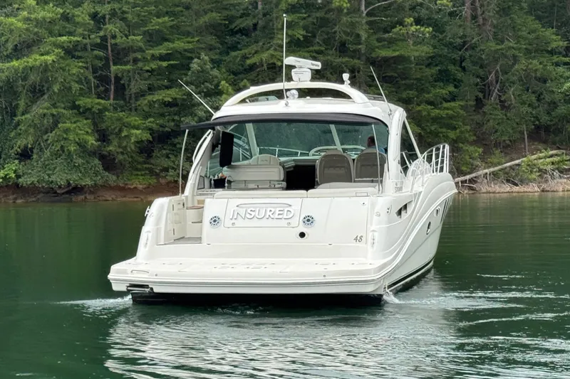 Slide: The Image of 2007 Sea Ray 48 Sundancer yacht cruising on a serene lake with lush forest backdrop. - 6