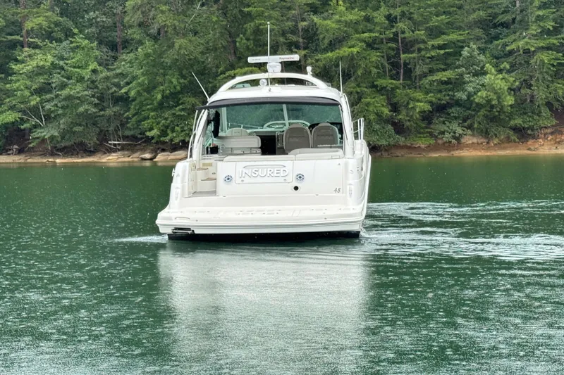 Slide: The Image of 2007 Sea Ray 48 Sundancer yacht on a serene lake with lush forest backdrop. - 7