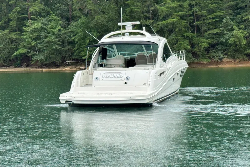 Slide: The Image of 2007 Sea Ray 48 Sundancer yacht on a serene lake with lush forest backdrop. - 8