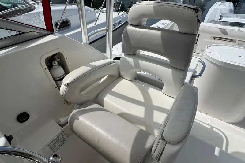 Slide: The Image of Captain's chair on 2005 Boston Whaler 305 Conquest boat, featuring white upholstery and armrests. - 12