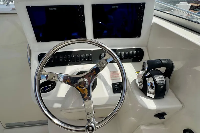Slide: The Image of Control panel of a 2005 Boston Whaler 305 Conquest boat with steering wheel and dual screens. - 14