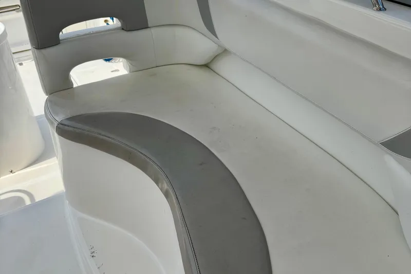 Slide: The Image of 2005 Boston Whaler 305 Conquest boat seating area, featuring white and gray upholstery. - 21