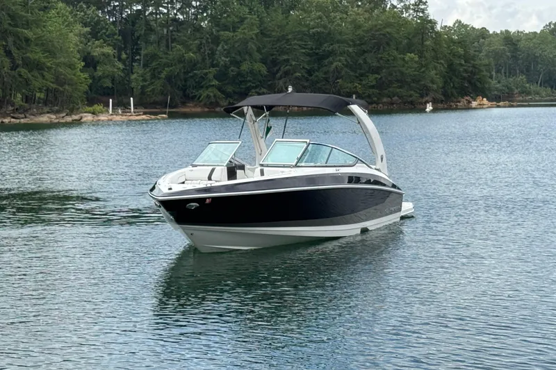 Slide: The Image of 2018 Regal 2500 Bowrider boat on a serene lake with lush forest backdrop. - 1