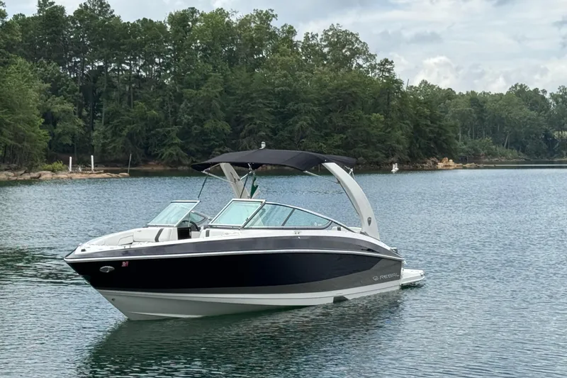 Slide: The Image of 2018 Regal 2500 Bowrider boat on a serene lake with forested shoreline. - 10