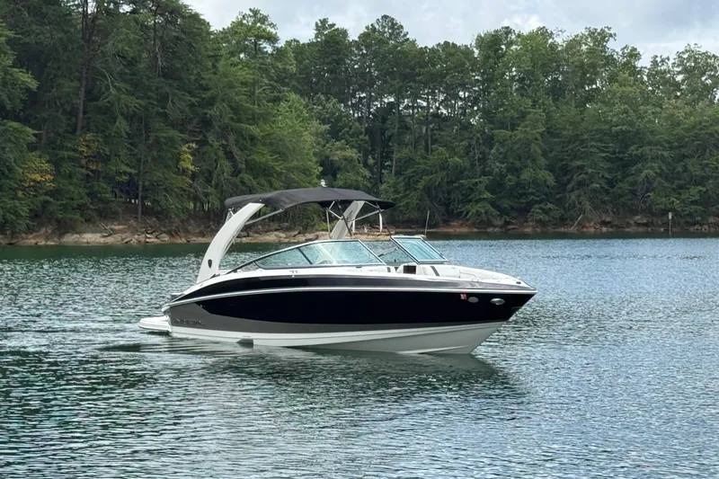 Slide: The Image of 2018 Regal 2500 Bowrider boat cruising on a serene lake with forested shoreline. - 5