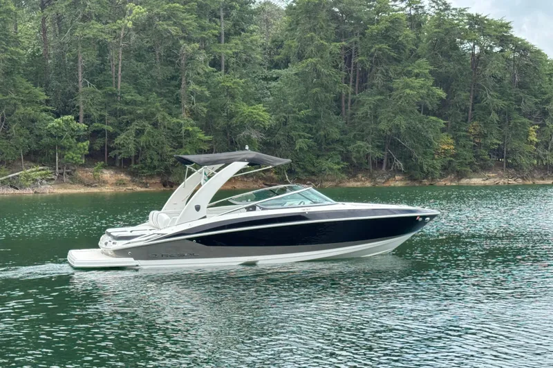 Slide: The Image of 2018 Regal 2500 Bowrider boat cruising on a serene lake with forested shoreline. - 7