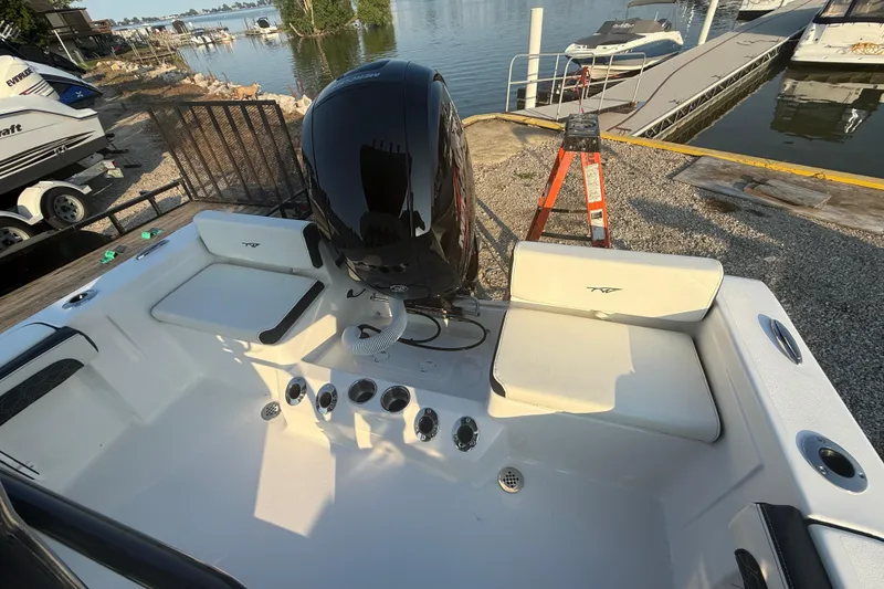 Slide: The Image of 2025 Tidewater 198 CC Adventure boat interior with seating and motor, dockside view. - 3