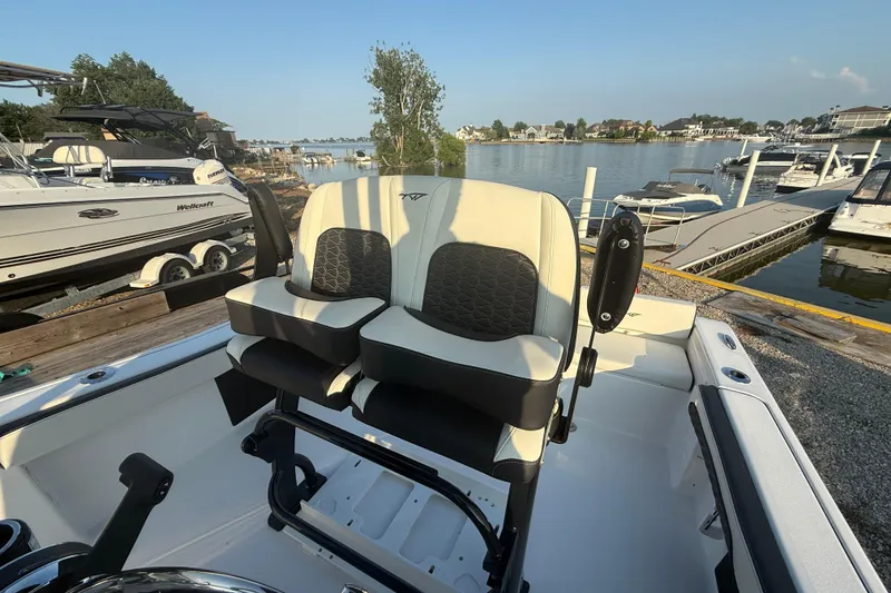 Slide: The Image of 2025 Tidewater 198 CC Adventure boat interior with dual seats, docked at marina. - 4