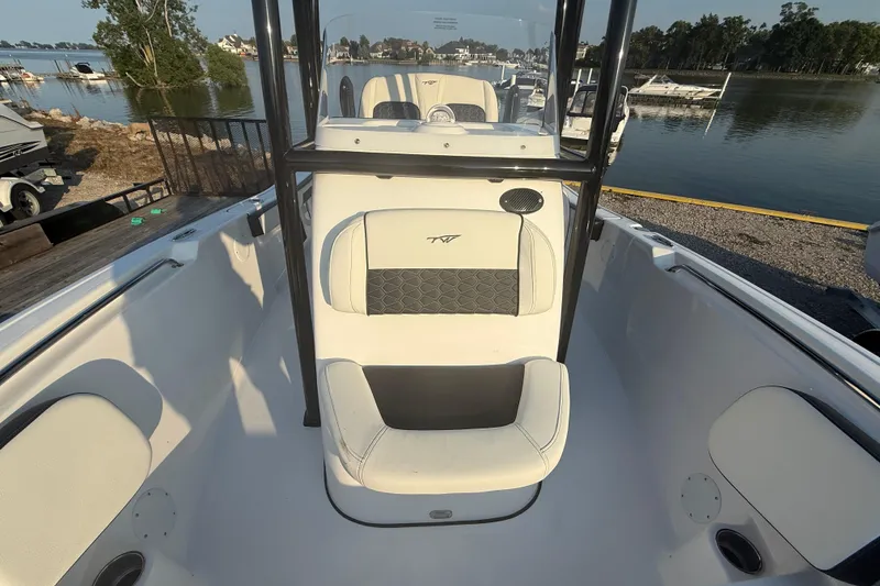 Slide: The Image of 2025 Tidewater 198 CC Adventure boat interior with seating, docked by a scenic lake. - 7