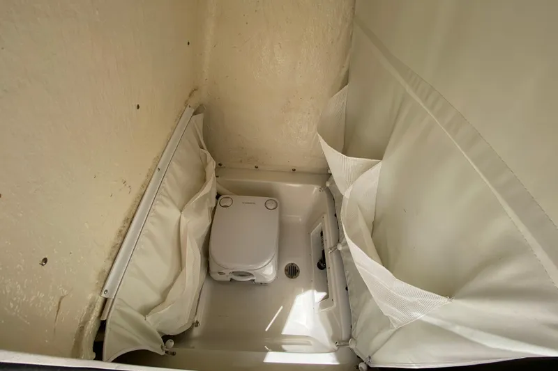 Slide: The Image of 2023 Key West 239 FS boat interior with compact portable toilet and storage pockets. - 102