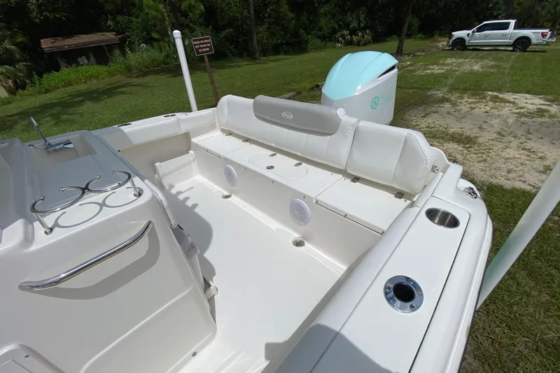 Slide: The Image of 2023 Key West 239 FS boat interior with seating and cup holders, parked on grass. - 14