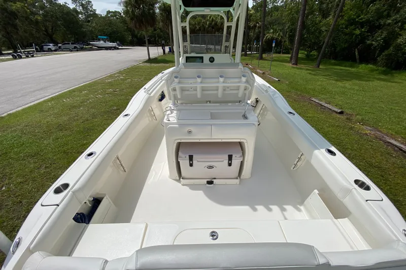 Slide: The Image of 2023 Key West 239 FS boat interior with seating and storage, parked near a grassy area. - 42
