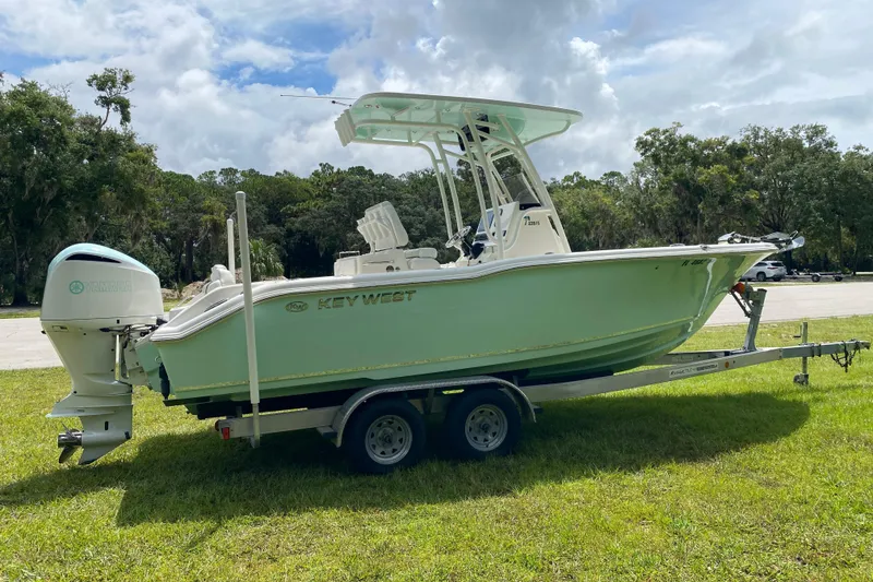 Slide: The Image of 2023 Key West 239 FS boat on trailer, parked on grass under cloudy sky. - 6