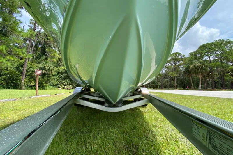 Slide: The Image of 2023 Key West 239 FS boat on trailer, viewed from below, in a lush green setting. - 9