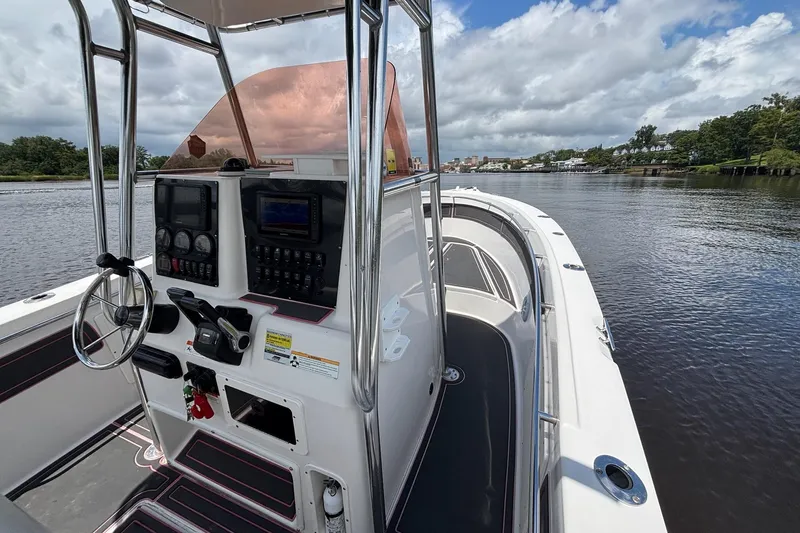 Slide: The Image of 2006 Seaswirl Striper 2601 boat interior with steering wheel and control panel on a calm river. - 8