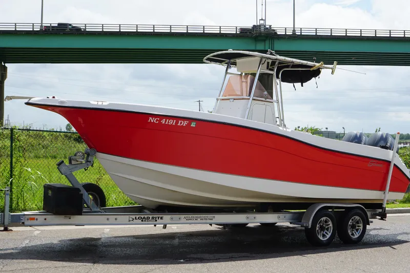 Slide: The Image of 2006 Seaswirl Striper 2601 boat on trailer, red hull, parked near bridge. - 6