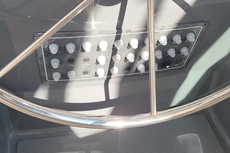 Slide: The Image of Control panel of a 2006 Tiara Yachts 4200 Open, featuring various switches and a metal steering wheel. - 27
