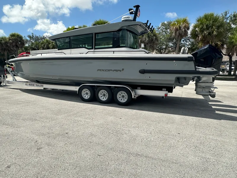 Slide: The Image of 2020 Axopar 37 XC CROSS CABIN boat on trailer, parked outdoors under blue sky. - 1