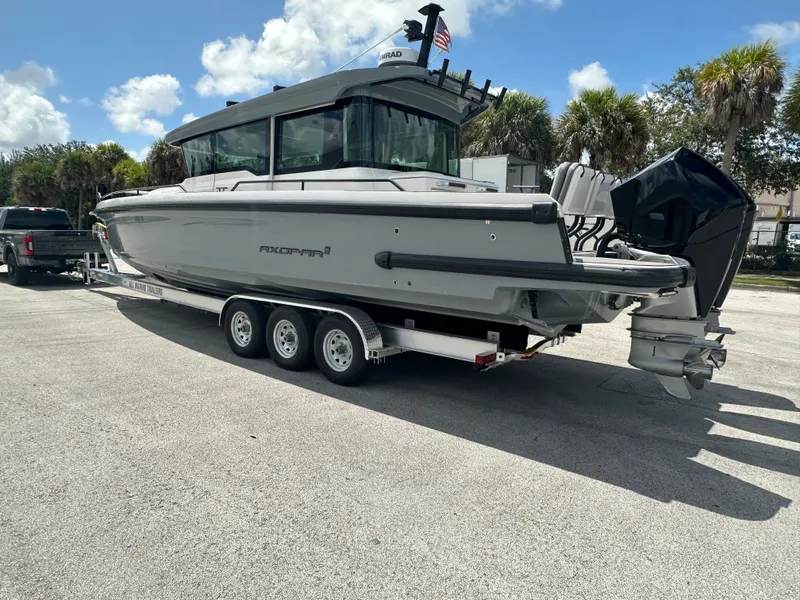 Slide: The Image of 2020 Axopar 37 XC CROSS CABIN boat on trailer, parked outdoors under a sunny sky. - 2