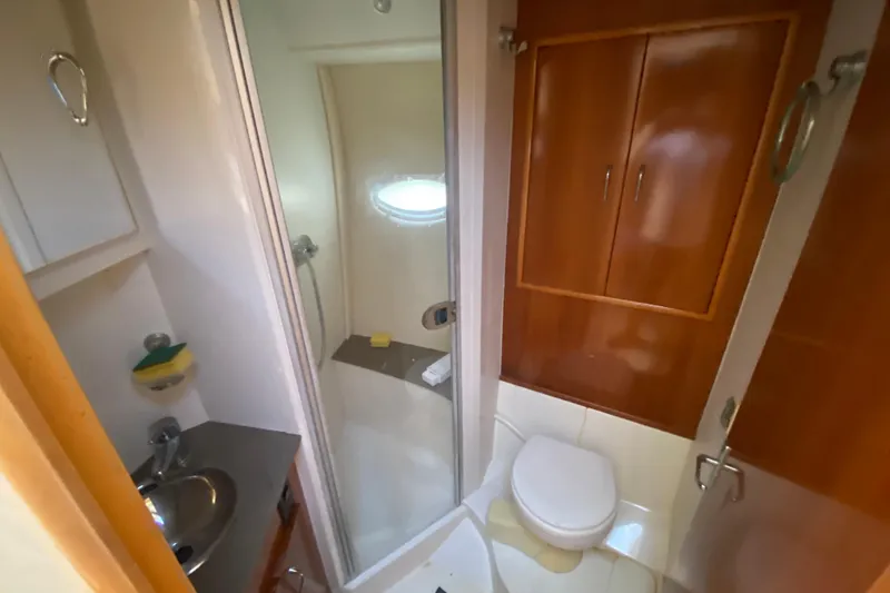 Slide: The Image of Bathroom interior of 2006 Carver 33 Super Sport yacht, featuring shower, sink, and wooden cabinetry. - 28