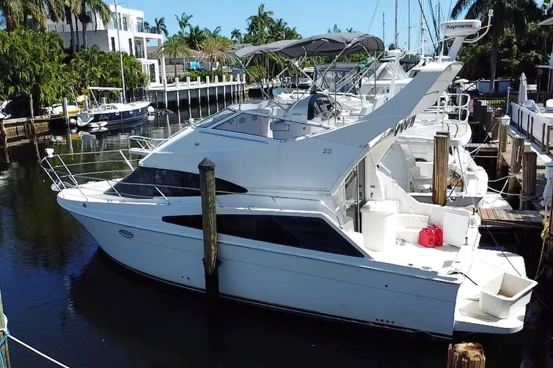 Slide: The Image of 2006 Carver 33 Super Sport yacht docked in a marina, surrounded by palm trees. - 3