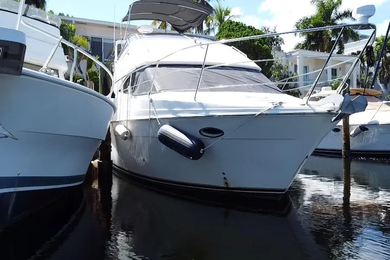 Slide: The Image of 2006 Carver 33 Super Sport yacht docked between boats, sunny day, palm trees in background. - 8