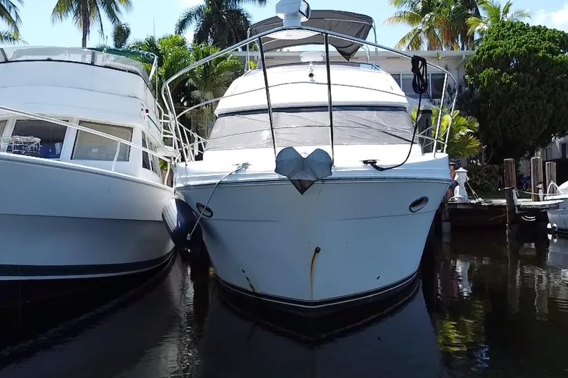 Slide: The Image of 2006 Carver 33 Super Sport yacht docked between palm trees and calm waters. - 9