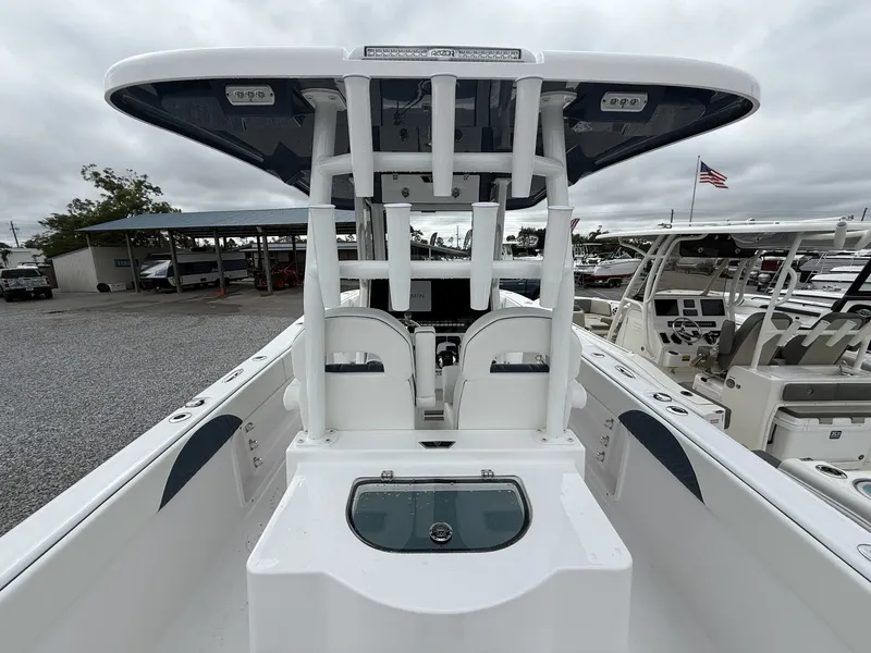 Slide: The Image of 2026 Twin Vee GFX2 260 boat interior with helm and seating, docked under cloudy skies. - 14