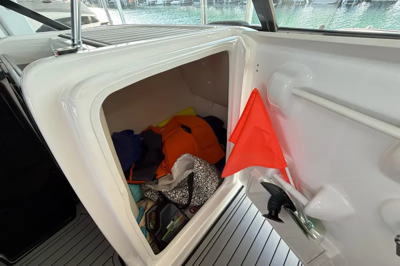 Slide: The Image of Storage compartment on 2018 Yamaha Boats 242 Limited S E-Series with life jackets and safety gear. - 22