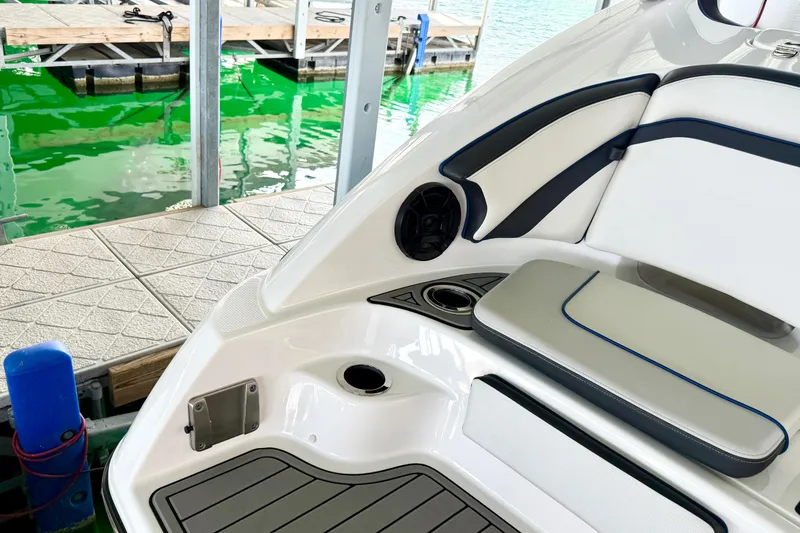 Slide: The Image of 2018 Yamaha Boats 242 Limited S E-Series interior near dock, featuring sleek seating and speaker. - 9