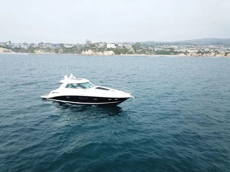 Slide: The Image of 2012 Sea Ray 450 Sundancer yacht cruising on open water near coastline. - 23