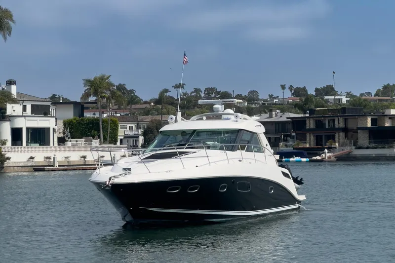 Slide: The Image of 2012 Sea Ray 450 Sundancer yacht cruising in a scenic waterfront area. - 25