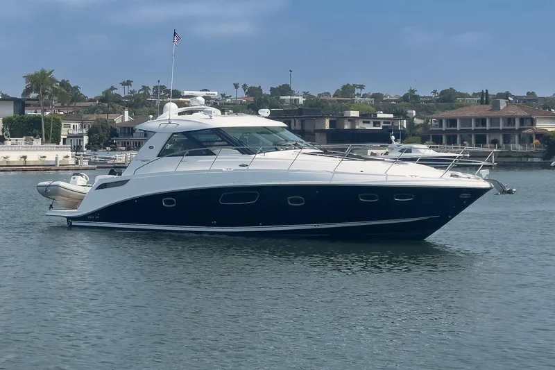Slide: The Image of 2012 Sea Ray 450 Sundancer yacht on calm water, with coastal homes in the background. - 26