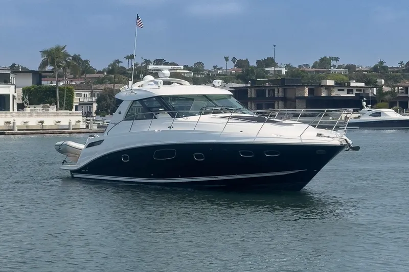 Slide: The Image of Luxury 2012 Sea Ray 450 Sundancer yacht on calm waters, with coastal homes in the background. - 27