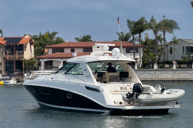 Slide: The Image of 2012 Sea Ray 450 Sundancer yacht cruising near waterfront homes with palm trees. - 28